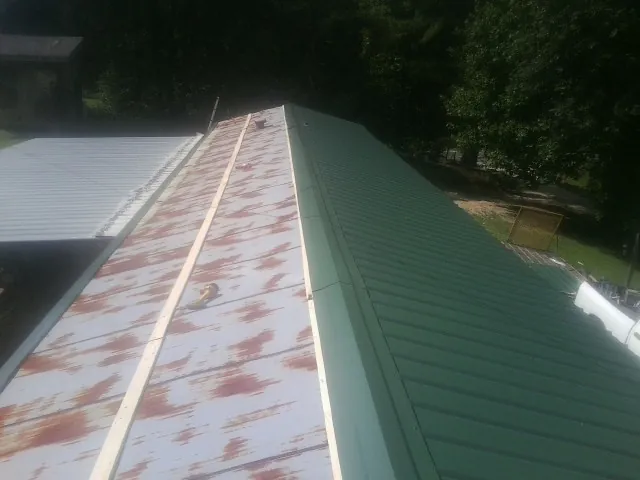 Old rusted panels beside newly installed green metal roofing — Wind Damage Roof Repair by Roofing Brothers in Keysville